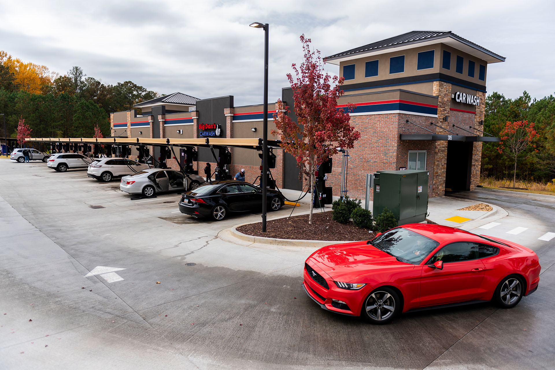A red sports car exits Big Dan's automatic soft-touch car wash in Woodstock, GA, looking radiant, shiny, and clean