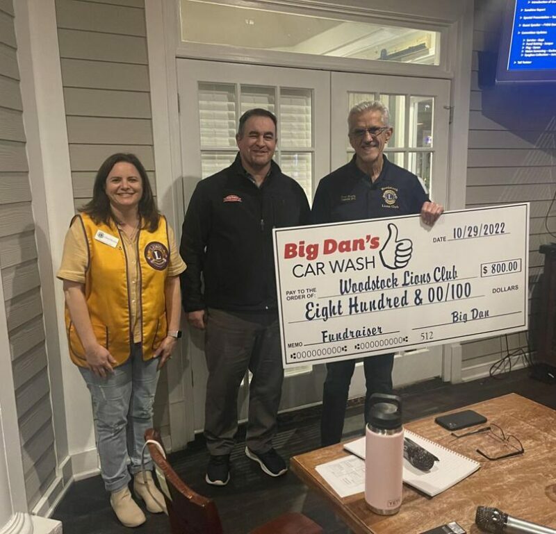 Big Dan's Team donates $800 to the Woodstock Lions Club, posing together with a large check